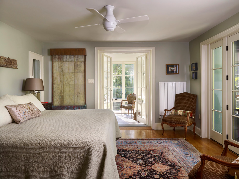 Cette image montre une grande chambre parentale traditionnelle avec un mur gris et un sol en bois brun.