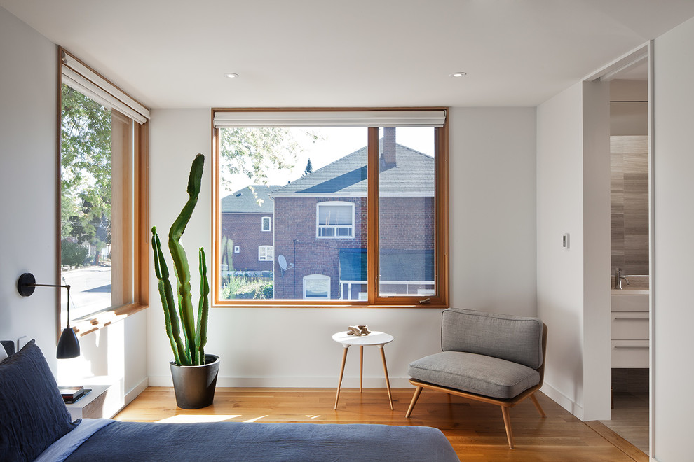 Foto de dormitorio principal moderno de tamaño medio sin chimenea con paredes blancas y suelo de madera en tonos medios