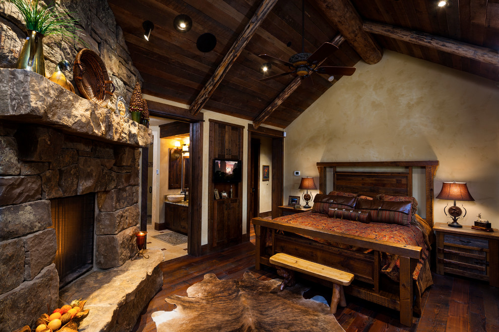 Inspiration for a large rustic master dark wood floor bedroom remodel in Other with beige walls, a standard fireplace and a stone fireplace