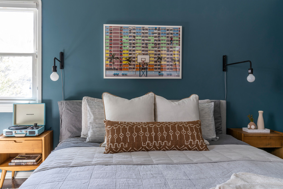 Modelo de dormitorio principal vintage de tamaño medio sin chimenea con paredes azules y suelo de madera oscura