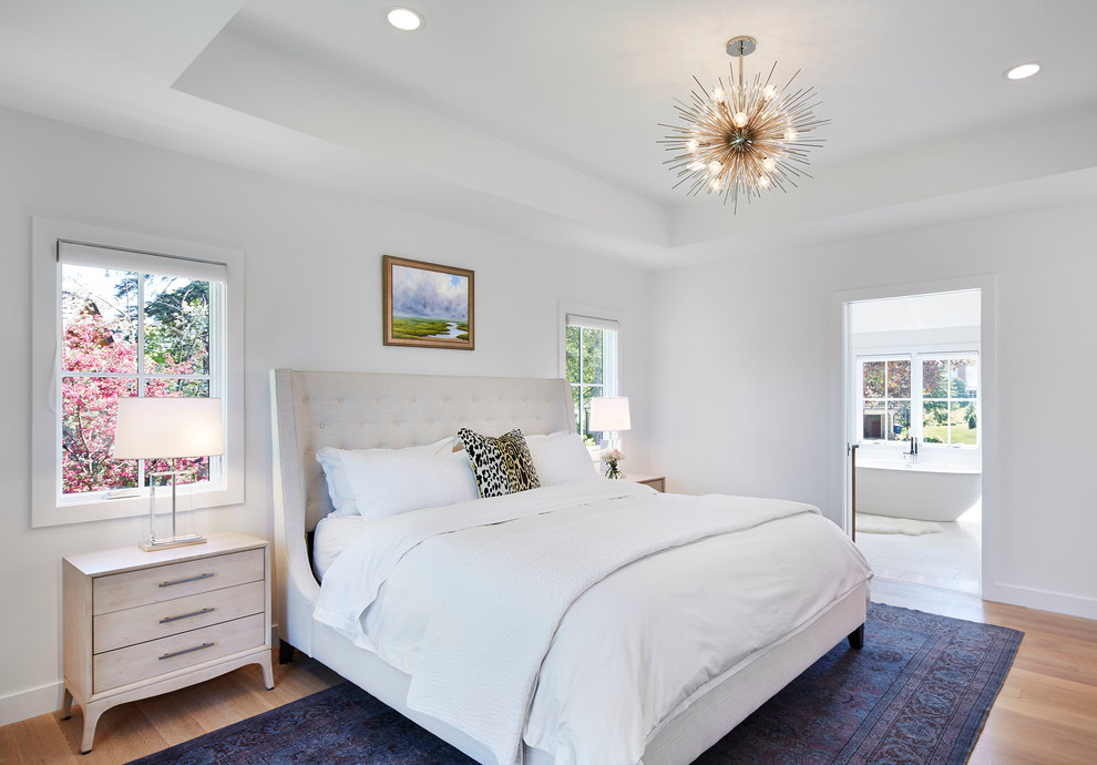 Ejemplo de dormitorio principal tradicional renovado de tamaño medio sin chimenea con paredes blancas, suelo de madera clara y suelo beige