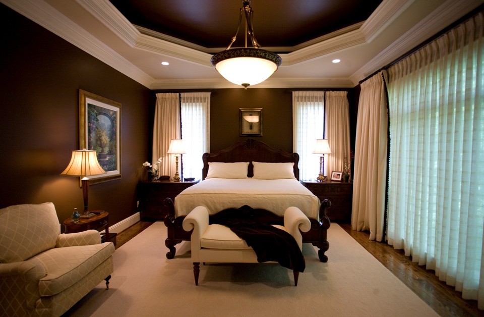 Immagine di una camera matrimoniale classica di medie dimensioni con pareti marroni, pavimento in laminato e pavimento marrone