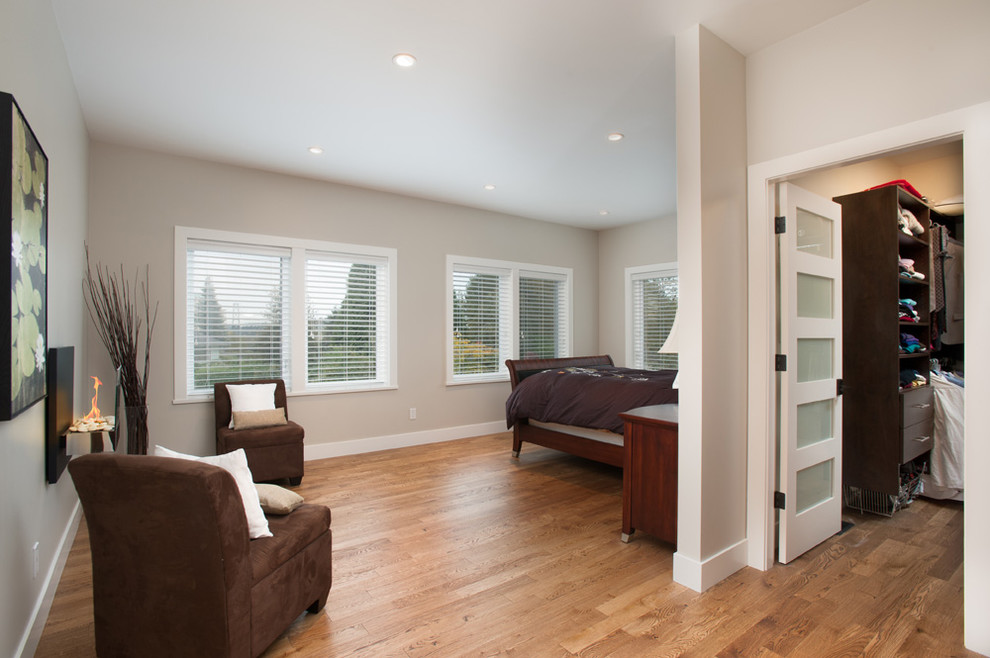 Cette image montre une chambre parentale design de taille moyenne avec un mur beige et un sol en bois brun.