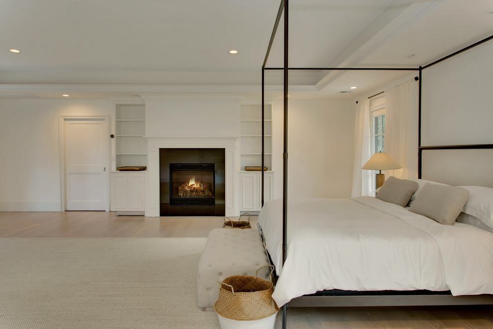 Свежая идея для дизайна: огромная хозяйская спальня в стиле неоклассика (современная классика) с белыми стенами, светлым паркетным полом, стандартным камином, фасадом камина из плитки и коричневым полом - отличное фото интерьера