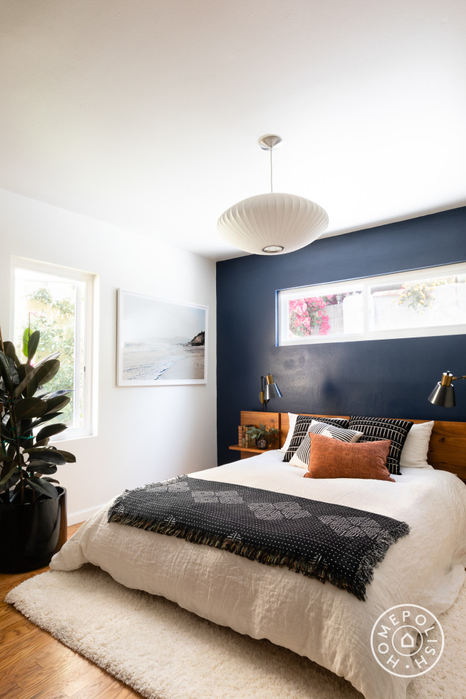 Small bohemian master bedroom in Los Angeles with blue walls, dark hardwood flooring and brown floors.
