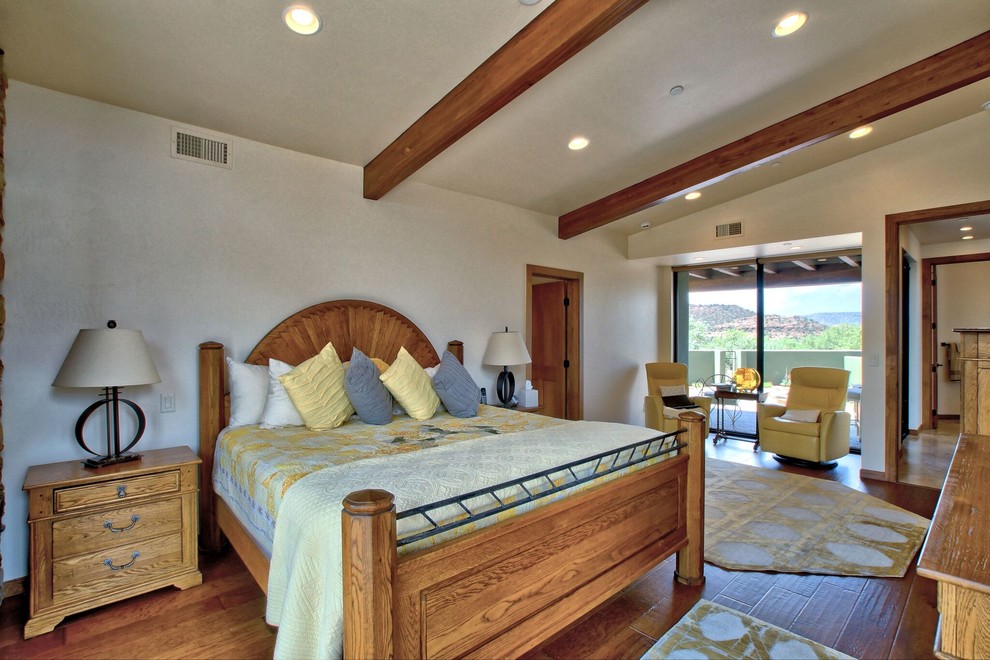 Cette photo montre une grande chambre parentale sud-ouest américain avec un mur beige, un sol en bois brun et aucune cheminée.