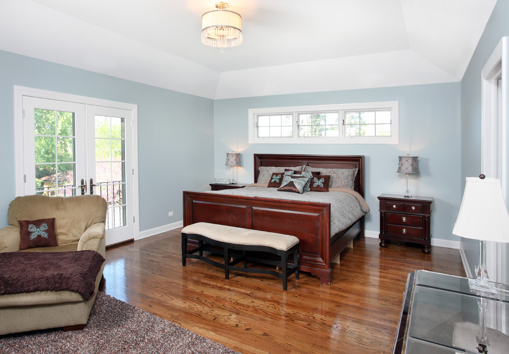 Exemple d'une grande chambre parentale chic avec un mur bleu et un sol en bois brun.