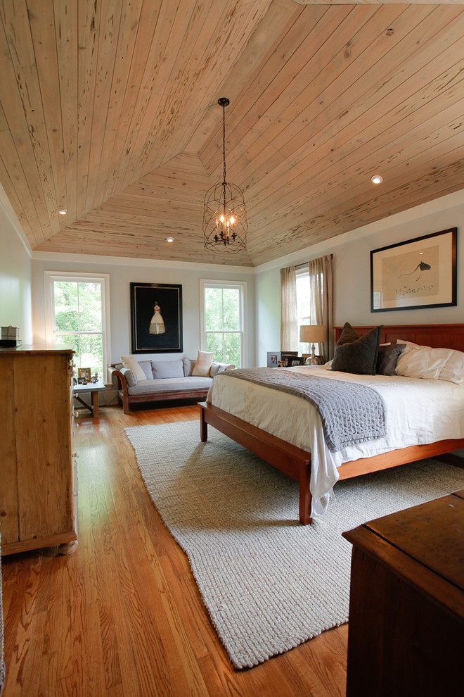 Modelo de dormitorio principal campestre de tamaño medio con paredes grises, suelo de madera en tonos medios y suelo marrón