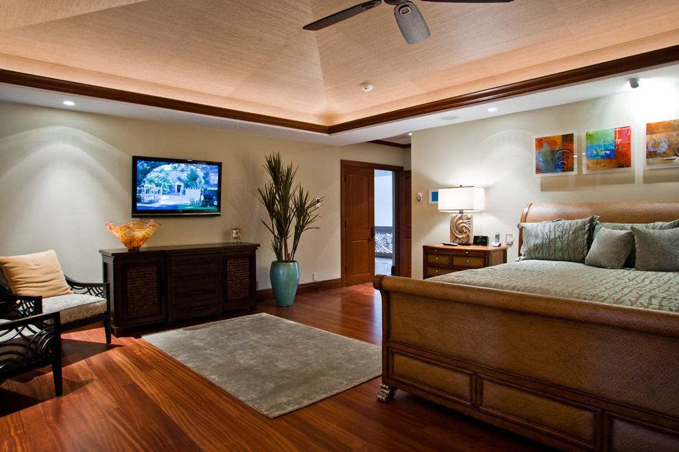 Modelo de dormitorio principal exótico grande sin chimenea con paredes beige, suelo de madera en tonos medios y suelo marrón