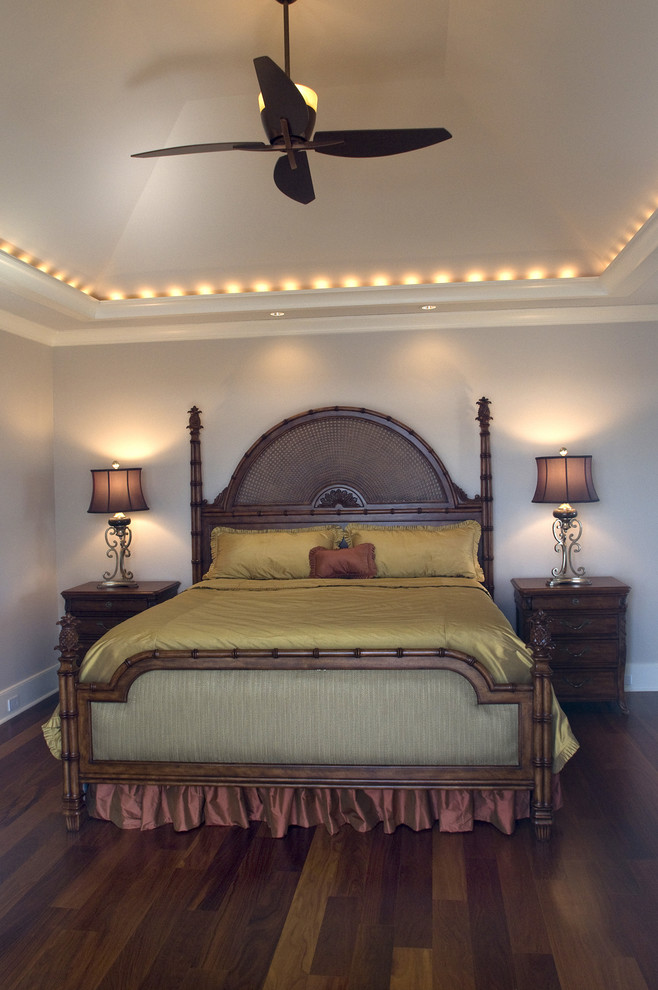 Modelo de dormitorio principal y abovedado marinero grande con paredes beige, suelo de madera en tonos medios, todas las chimeneas, marco de chimenea de madera y suelo marrón