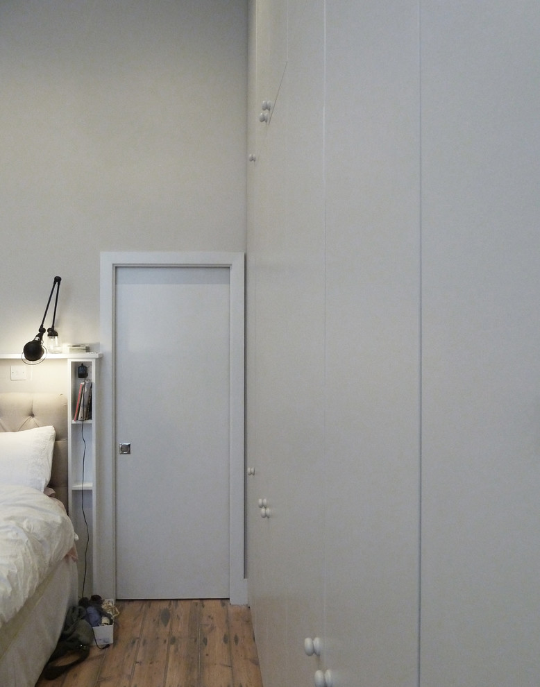 Ejemplo de dormitorio principal actual de tamaño medio con paredes beige y suelo de madera clara