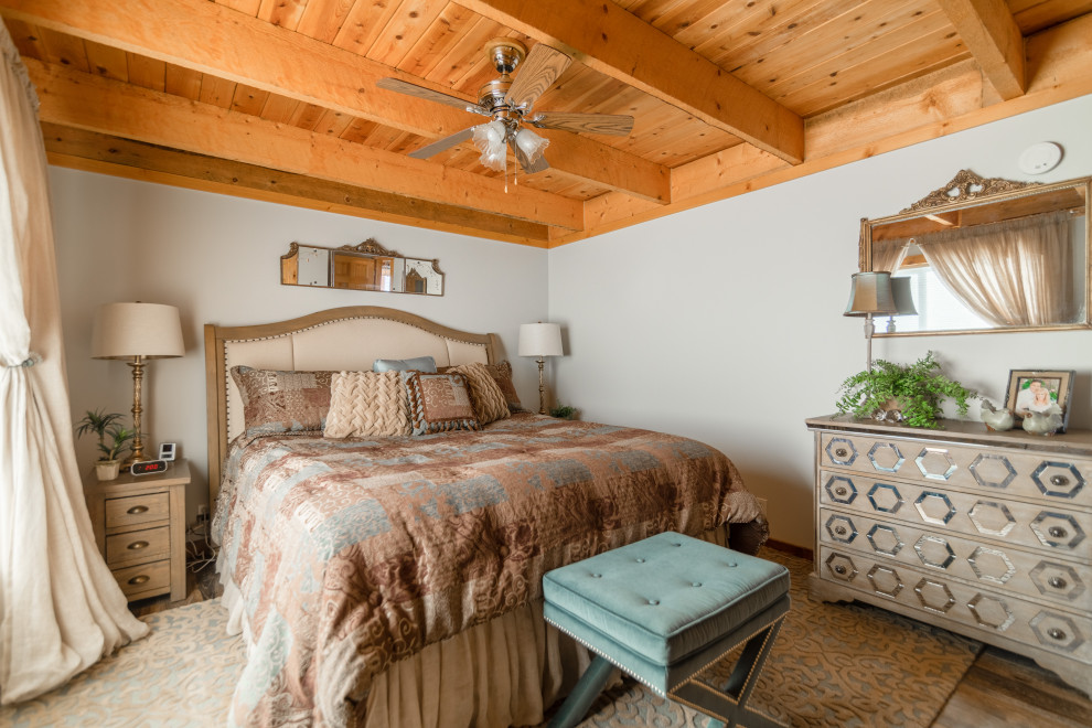 На фото: спальня в стиле рустика с белыми стенами, темным паркетным полом, коричневым полом, балками на потолке и деревянным потолком с
