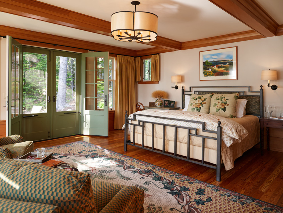 Cette photo montre une chambre parentale craftsman avec un mur beige et un sol en bois brun.
