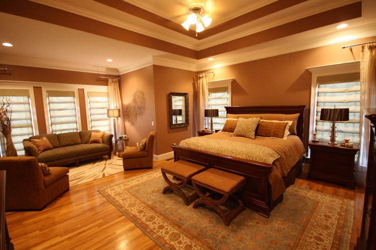 他の地域にある広いトラディショナルスタイルのおしゃれな主寝室 (茶色い壁、無垢フローリング、暖炉なし) のインテリア