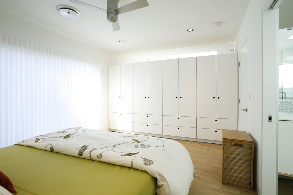 На фото: хозяйская спальня в скандинавском стиле с белыми стенами и светлым паркетным полом без камина с