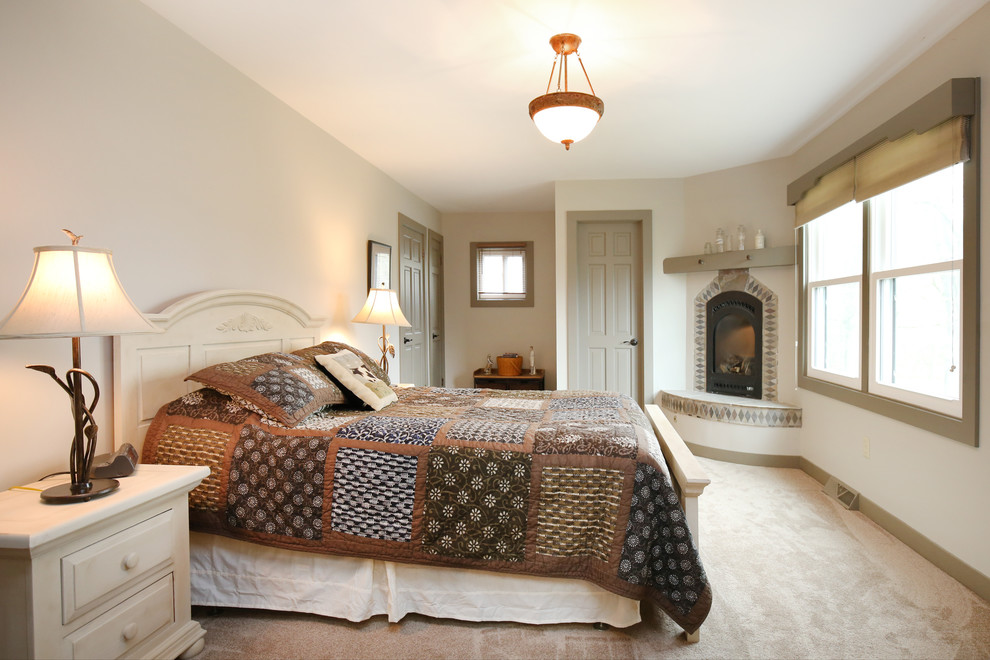 Bedroom - mid-sized traditional master carpeted bedroom idea in Grand Rapids with beige walls, a corner fireplace and a stone fireplace