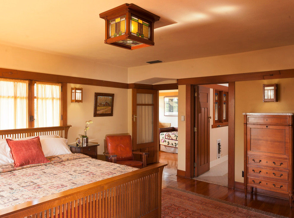 Пример оригинального дизайна: большая хозяйская спальня в стиле кантри с желтыми стенами и паркетным полом среднего тона