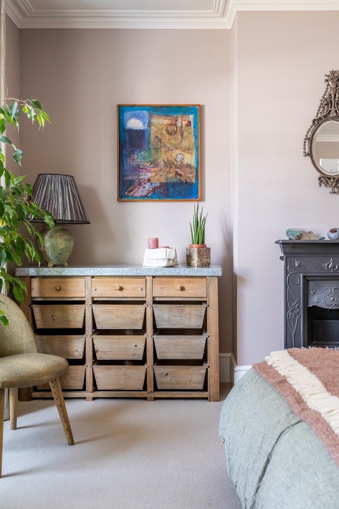 Inspiration for an eclectic master bedroom in Cambridgeshire with pink walls, carpet, a standard fireplace, a metal fireplace surround and grey floors.