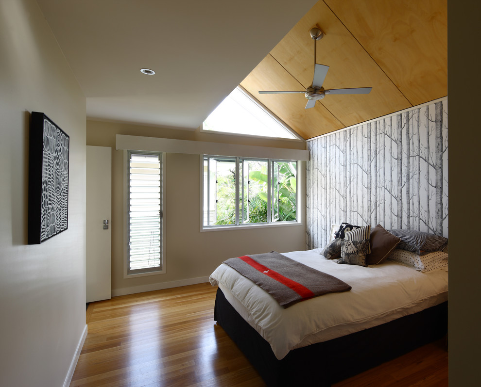 Idée de décoration pour une chambre parentale design avec un mur multicolore et un sol en bois brun.