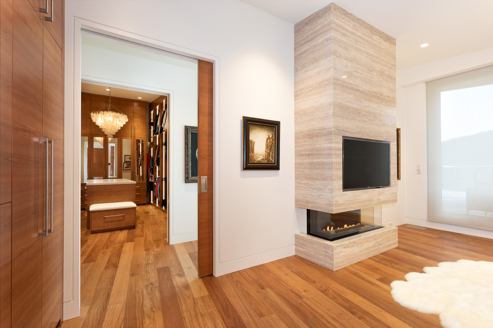 Geräumiges Modernes Gästezimmer mit brauner Wandfarbe, hellem Holzboden, Gaskamin, Kaminumrandung aus Stein und beigem Boden in Vancouver