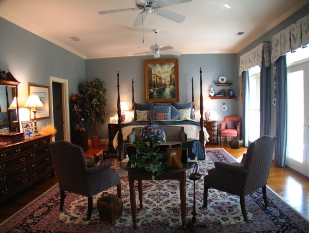 Cette image montre une grande chambre parentale traditionnelle avec un mur bleu, un sol en bois brun et aucune cheminée.