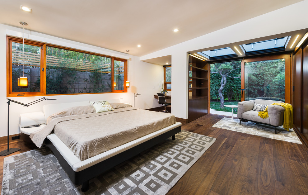 Diseño de dormitorio principal moderno de tamaño medio con paredes blancas y suelo de madera en tonos medios