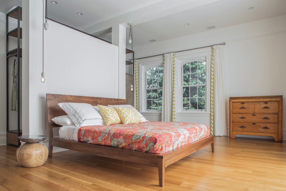 Modelo de dormitorio principal nórdico grande sin chimenea con paredes blancas, suelo de madera en tonos medios y suelo marrón