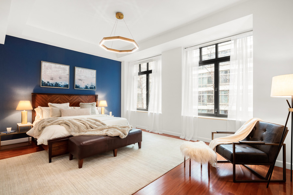 Foto di un'ampia camera matrimoniale moderna con pareti blu, pavimento in legno massello medio e pavimento marrone