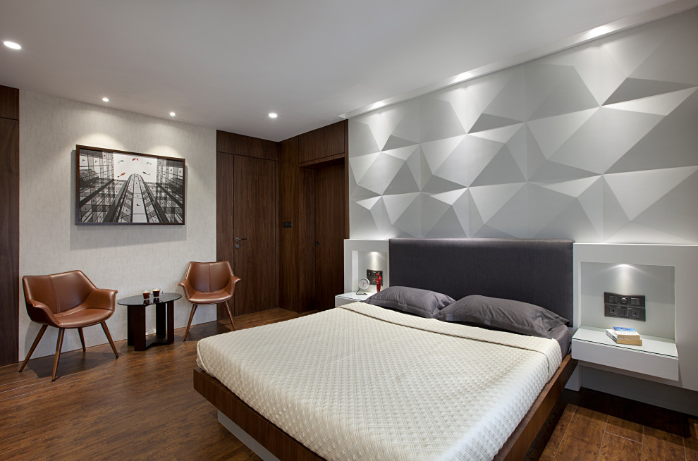 Photo of a large contemporary master and grey and brown bedroom in Mumbai with white walls, medium hardwood flooring and brown floors.