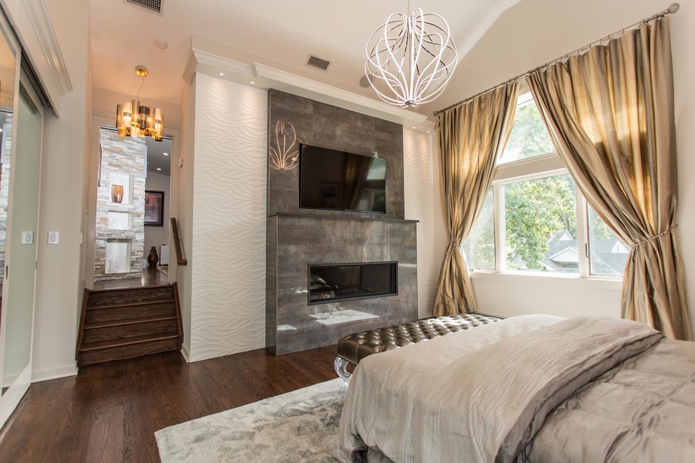 This is an example of a large contemporary master bedroom in New York with beige walls, dark hardwood flooring and a tiled fireplace surround.
