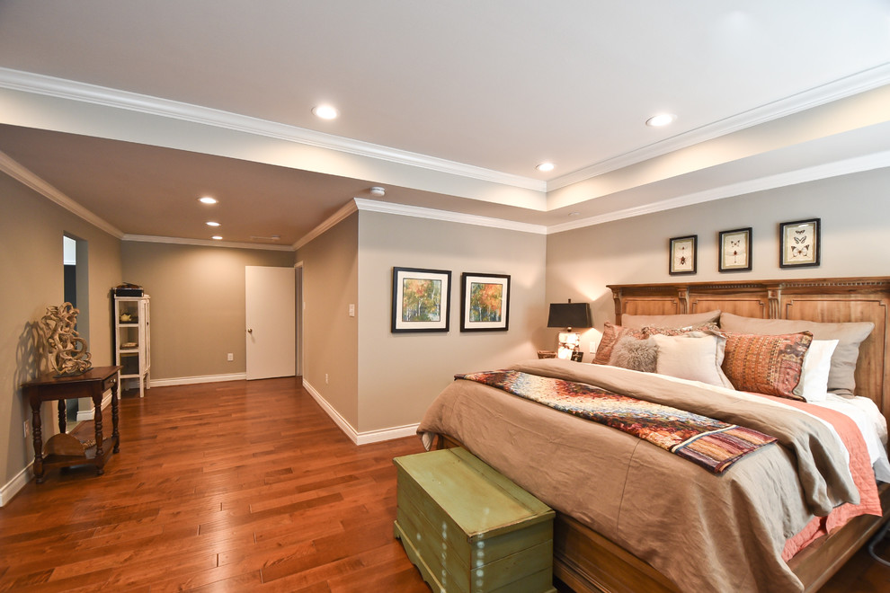 Cette image montre une chambre parentale traditionnelle avec un mur gris et un sol en bois brun.