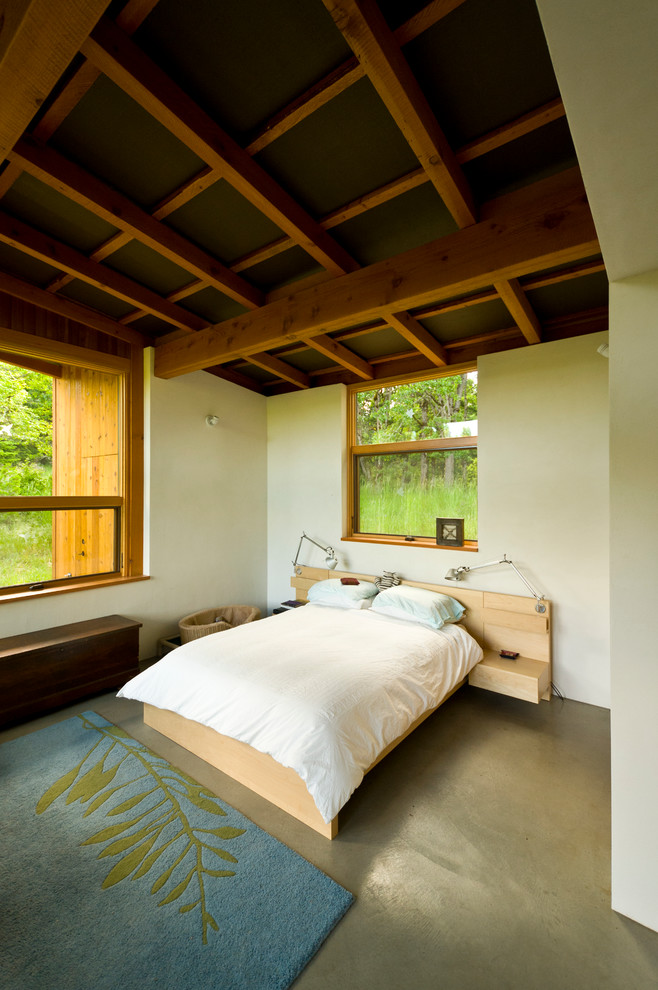 Modelo de dormitorio principal contemporáneo pequeño con paredes beige y suelo de cemento