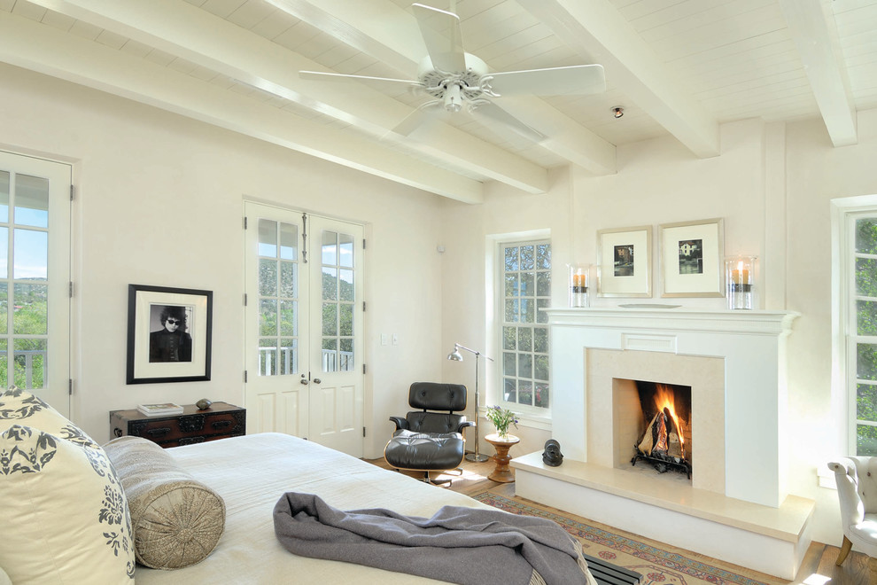 Inspiration for a medium sized classic master bedroom in Albuquerque with white walls, a standard fireplace, a wooden fireplace surround and light hardwood flooring.