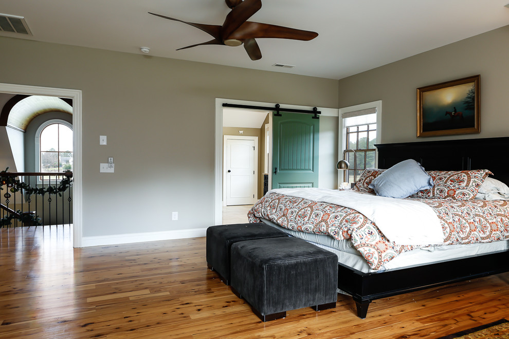 Imagen de dormitorio principal de estilo de casa de campo grande sin chimenea con paredes grises y suelo de madera en tonos medios
