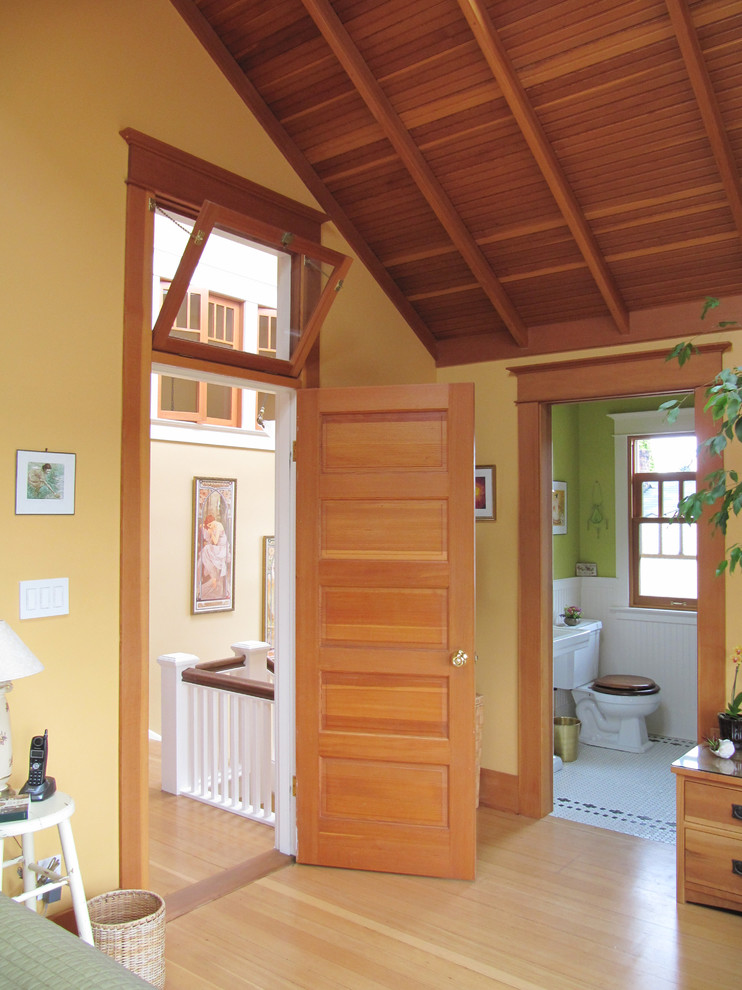 Exemple d'une très grande chambre parentale craftsman avec un mur jaune et parquet clair.