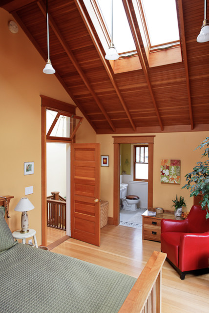 This is an example of an expansive traditional master bedroom in Seattle with yellow walls and light hardwood flooring.