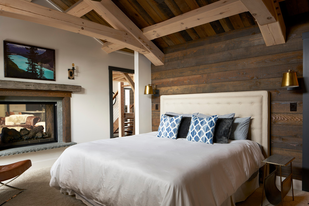 Cette photo montre une chambre montagne de taille moyenne avec un mur blanc, une cheminée double-face, un sol beige et un manteau de cheminée en bois.