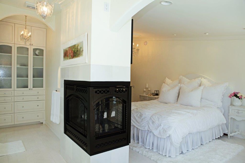 Diseño de dormitorio principal contemporáneo de tamaño medio con paredes beige, suelo de baldosas de cerámica, marco de chimenea de metal y chimenea de doble cara