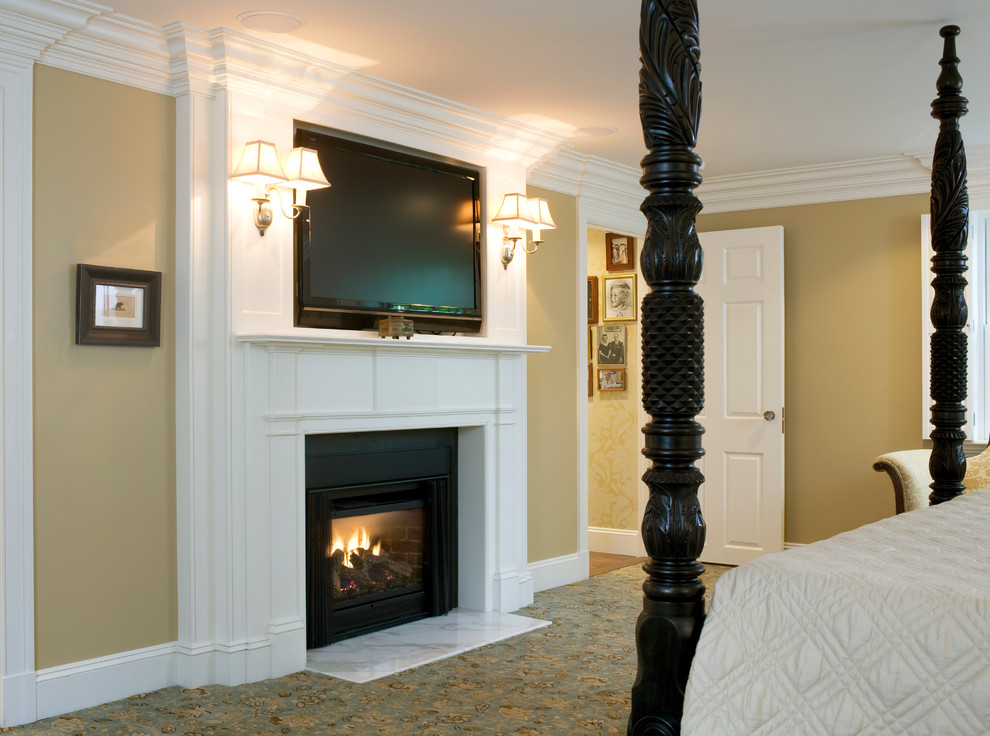 Cette image montre une grande chambre avec un mur beige, une cheminée standard, un manteau de cheminée en pierre et un sol multicolore.