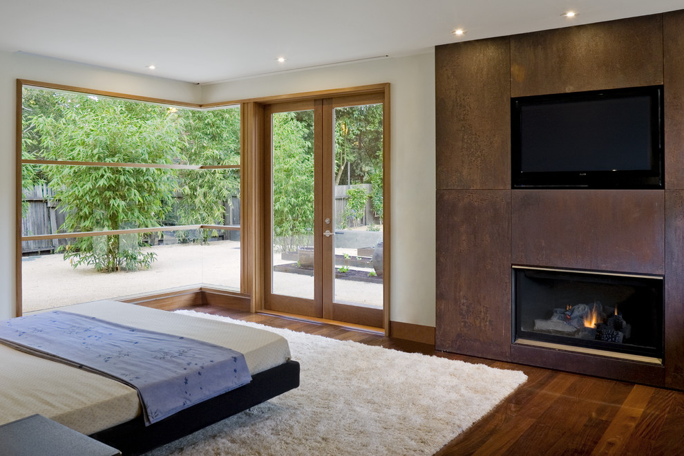 Идея дизайна: хозяйская спальня в современном стиле с бежевыми стенами, темным паркетным полом, стандартным камином и фасадом камина из металла