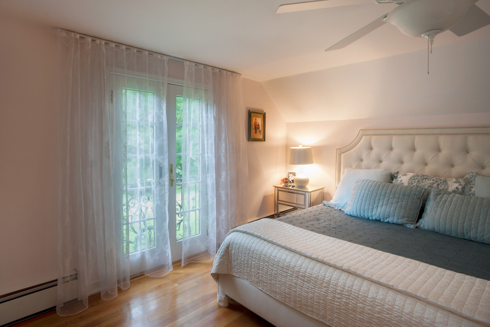 Imagen de dormitorio principal actual de tamaño medio sin chimenea con paredes rosas, suelo de madera clara y suelo marrón