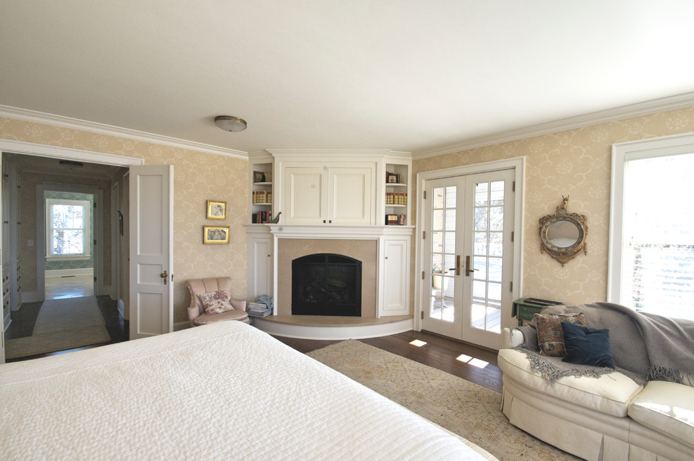 Geräumiges Klassisches Hauptschlafzimmer mit beiger Wandfarbe, braunem Holzboden, Eckkamin und Kaminumrandung aus Stein in Minneapolis