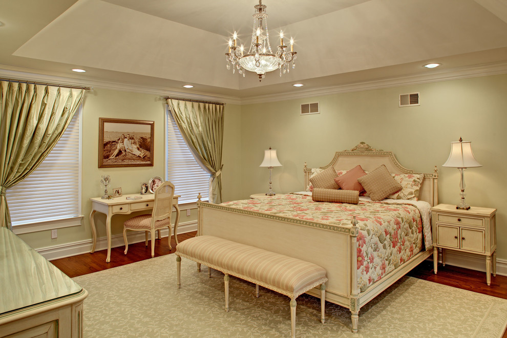 Modelo de dormitorio principal y blanco tradicional grande con paredes verdes, suelo de madera en tonos medios, suelo marrón y bandeja