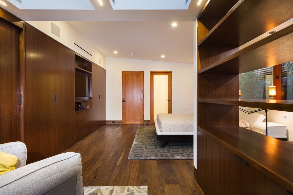 Imagen de dormitorio principal moderno de tamaño medio sin chimenea con paredes blancas y suelo de madera en tonos medios