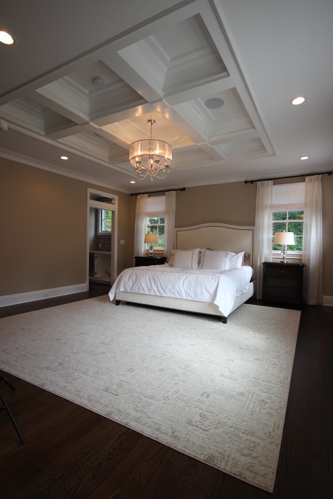 Modelo de dormitorio principal tradicional renovado grande con suelo de madera oscura y paredes beige