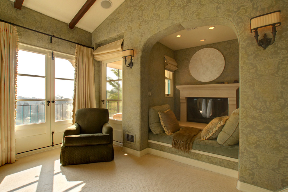 Стильный дизайн: огромная хозяйская спальня в средиземноморском стиле с зелеными стенами, ковровым покрытием и стандартным камином - последний тренд