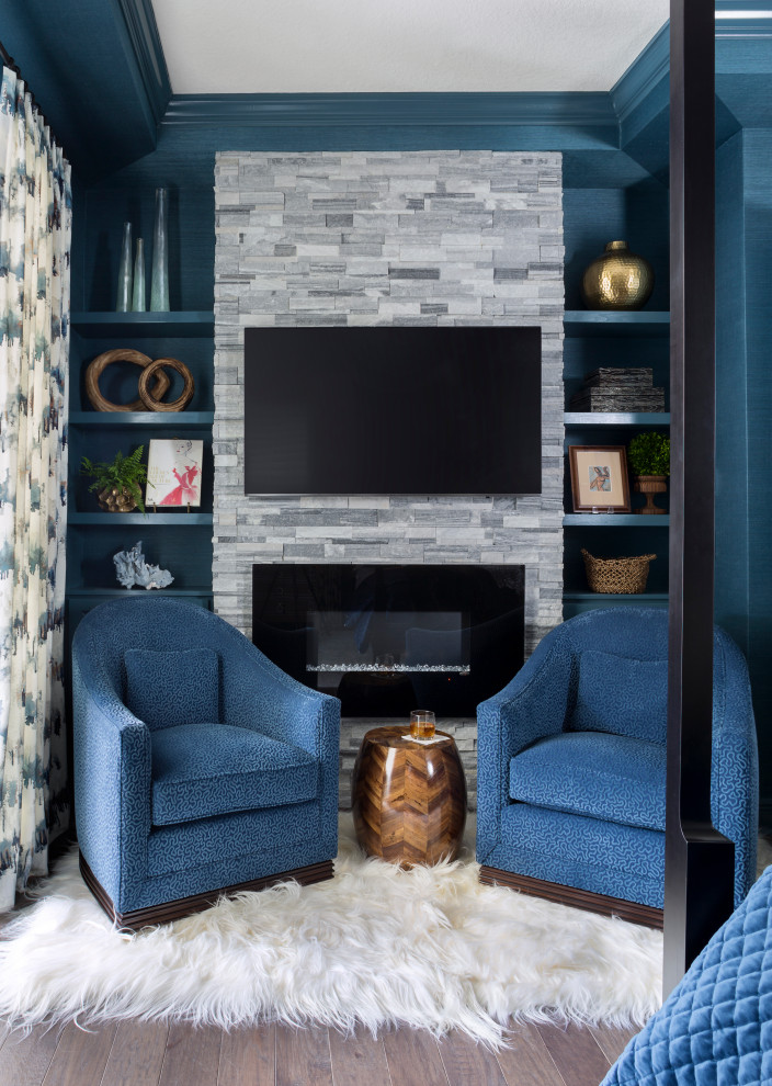 タンパにある広いトラディショナルスタイルのおしゃれな主寝室 (青い壁、無垢フローリング、標準型暖炉、積石の暖炉まわり、茶色い床)