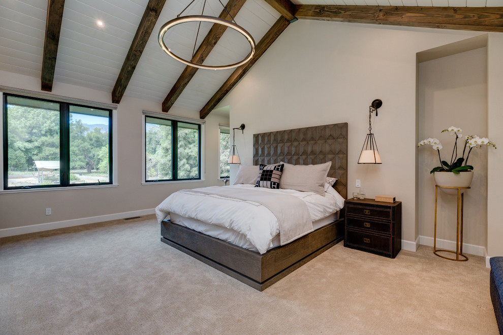 Modelo de dormitorio principal moderno grande con paredes beige, moqueta, todas las chimeneas, marco de chimenea de madera y suelo beige