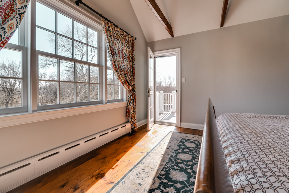Imagen de dormitorio principal tradicional renovado de tamaño medio sin chimenea con paredes grises y suelo de madera en tonos medios