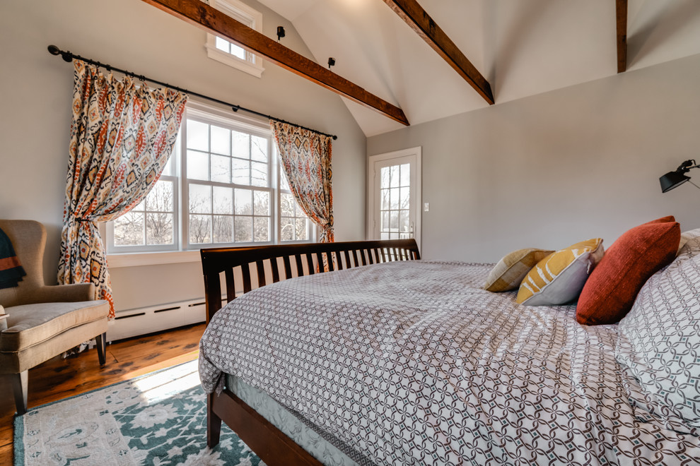 Modelo de dormitorio principal tradicional renovado de tamaño medio sin chimenea con paredes grises y suelo de madera en tonos medios